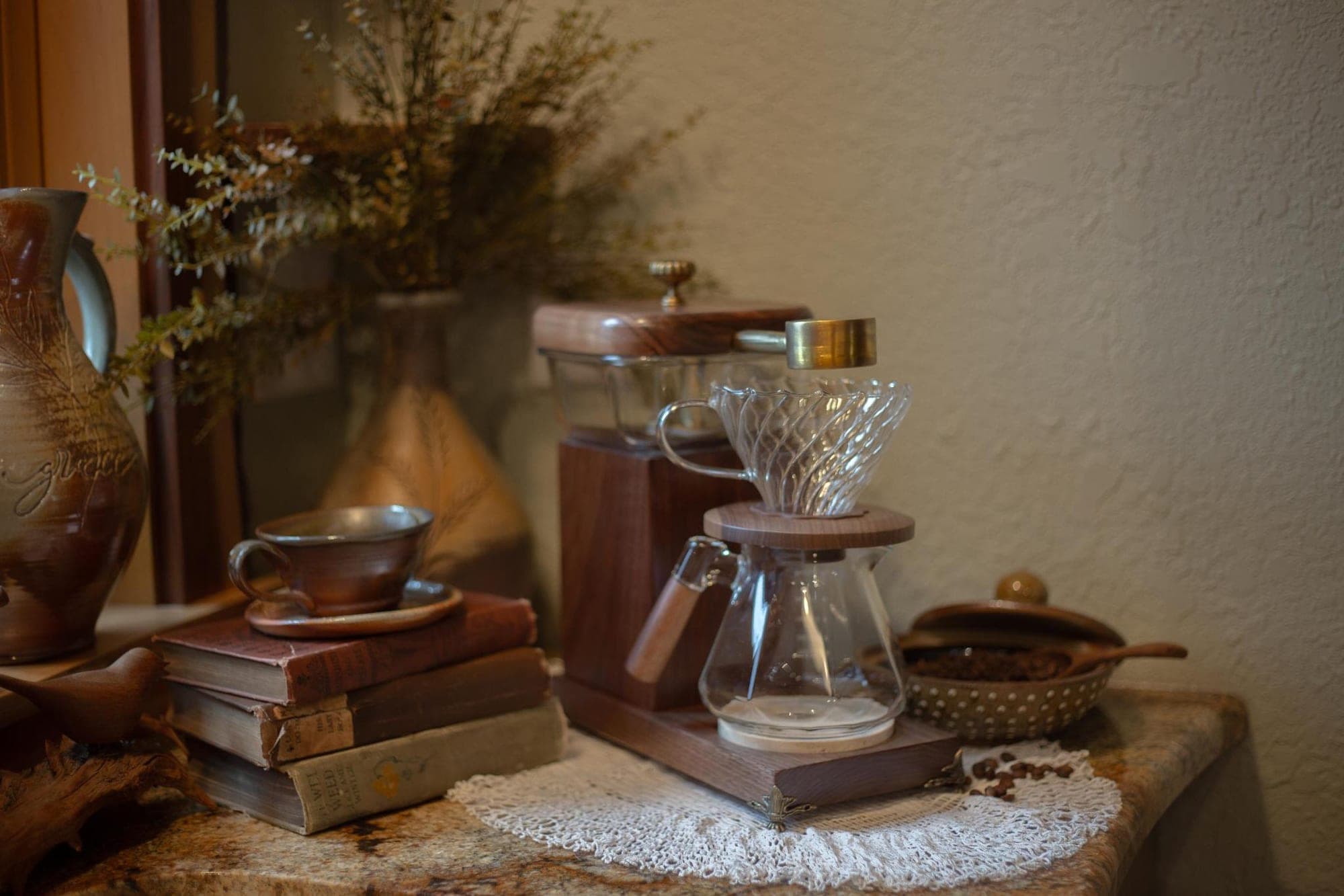 The Heritage Drip holding a coffee corner — stacked old books, a stoneware cup, dried flowers, and a bowl of beans on a granite counter